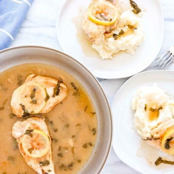 Over view of Lemon Basil Chicken with 2 Chicken Breast in Sauté pan with the sauce. 2 white plates with Mashed Potatoes, the lemon basil chicken and sauce with 2 forks. www.atwistedplate.com/lemon-basil-chicken/