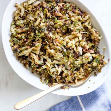 Close up of a bowl Garlic, Onion and Brussel sprouts. There is a blue towel with thin white stripes behind it. https://www.atwistedplate.com/garlic--onion-brussel-sprouts