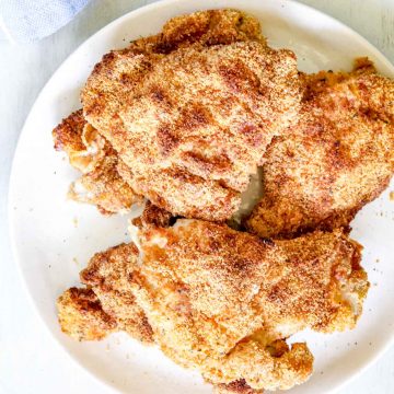 Image of Whole30 Air-fryer 5 chicken thighs on a round white plate. https://www.atwistedplate.com/whole30-air-fryer-chicken-thighs/